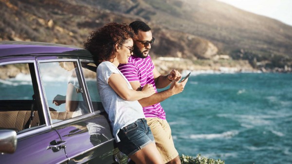 Microsaving, the key to an economic downturn Man and woman on beach looking at phone