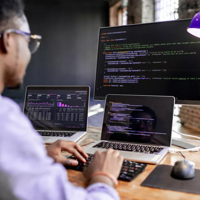 Man working on 3 computers
