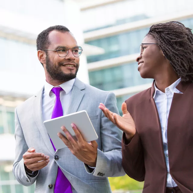 man and woman talking outside with tablet