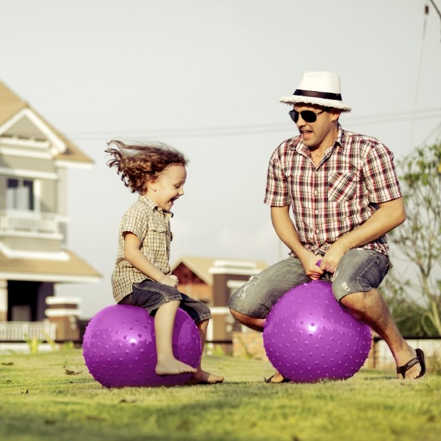 man and child playing on bouncy ball