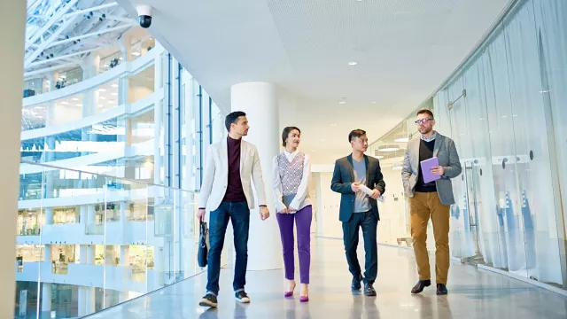 Image of officemates walking and discussing in office hallway