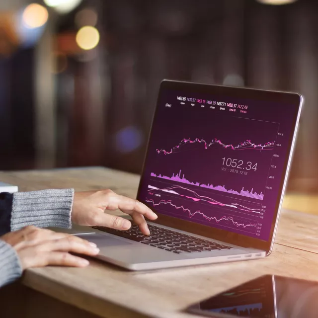 Image of laptop with graph, and hands typing