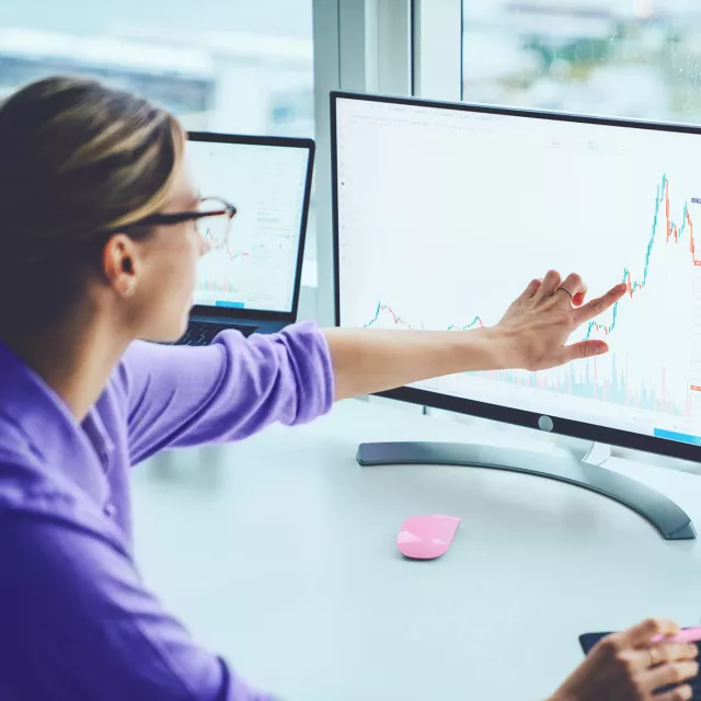 Image of woman pointing at graph in monitor