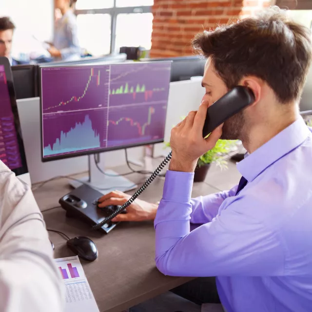 Image of man on phone while in front of computer