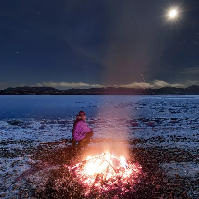Image of person beside a bonfire in snowy landscape
