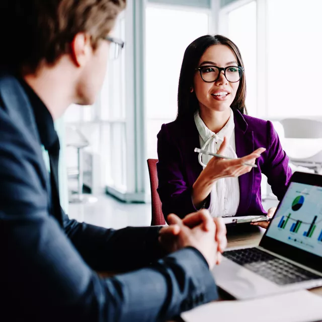 Image of woman explaining to officemate with laptop