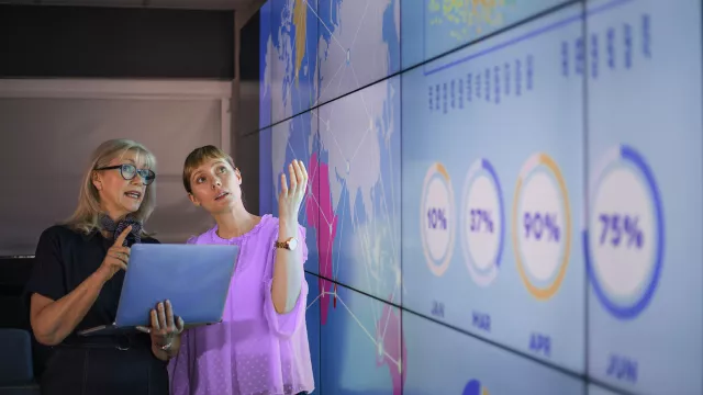 Image of women discussing graphs in screens