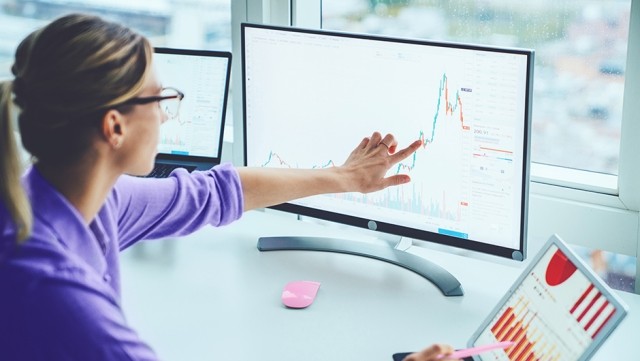 Image of woman pointing at graph in monitor