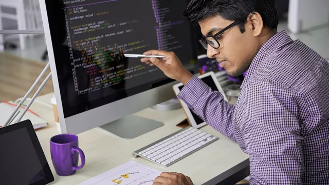 Image of man pointing at code in monitor
