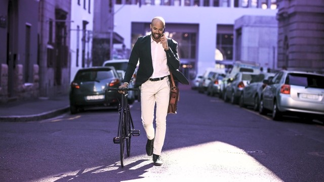 Image of man on mobile phone walking with bike