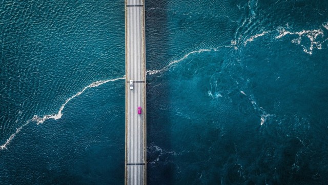 Image of two cars on a bridge over the ocean 