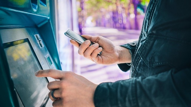 Image of person using mobile phone and ATM