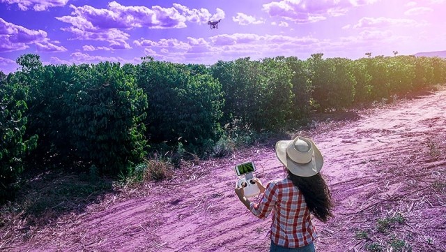 Image of woman flying a drone above a field