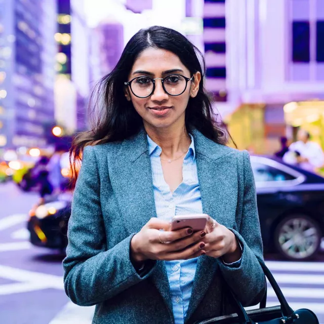 Image of woman with mobile phone walking in pedestrian lane