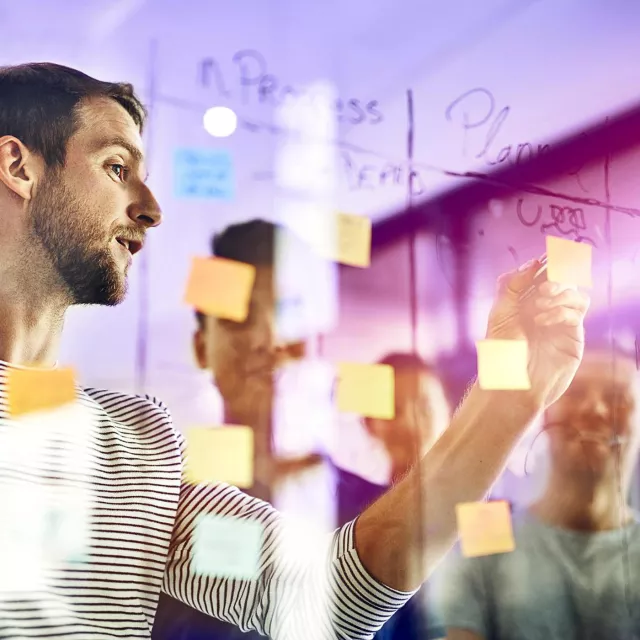 Image of man pointing at post-it in board