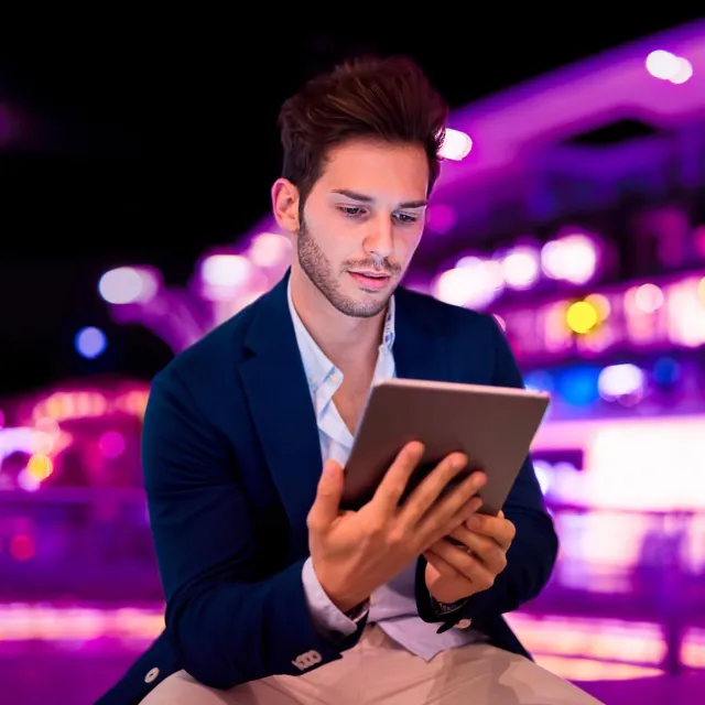 Image of a man looking at tablet outside at night
