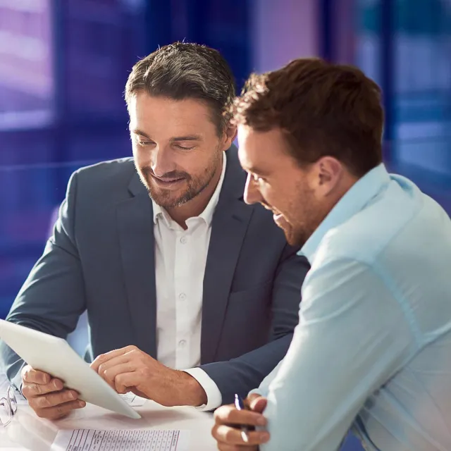 Image of two men discussing with tablet in hand