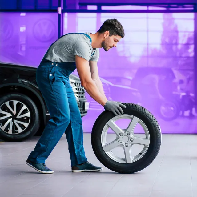 Image of mechanic pushing a tire in a garage
