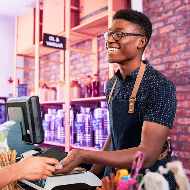 Image of man behind a cashier collecting digital payment