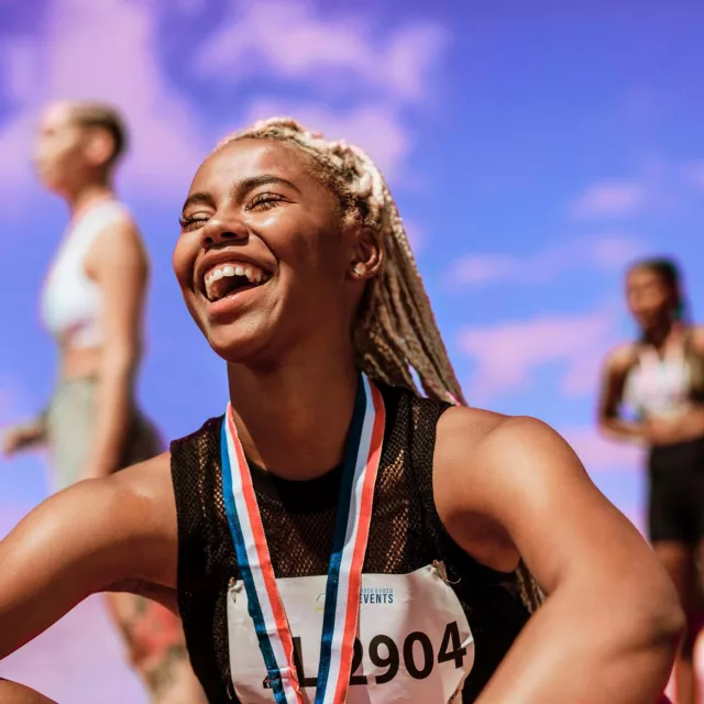 Image of woman in a race smiling, wearing a medal