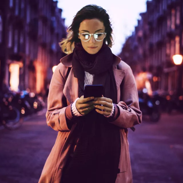 Image of a person standing in the middle of the street while staring at a smartphone