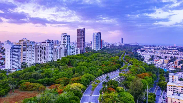 Image of highway next to high floor buildings and green trees
