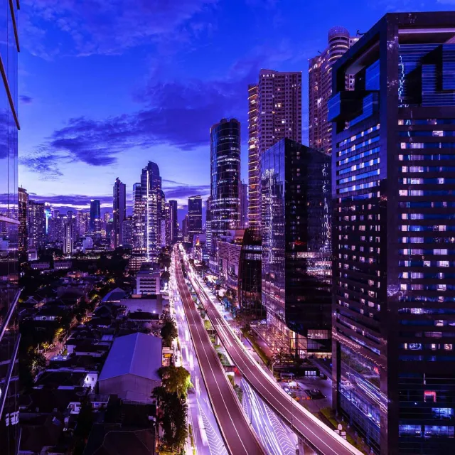 Vibrant city skyline at night with light trails and illuminated skyscrapers.