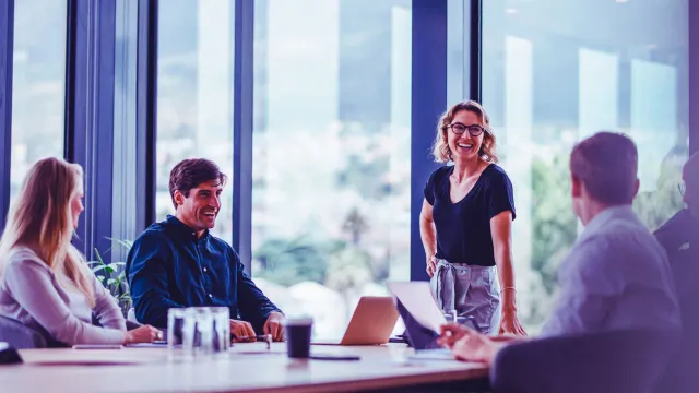 Image of woman standing and smiling in front of team