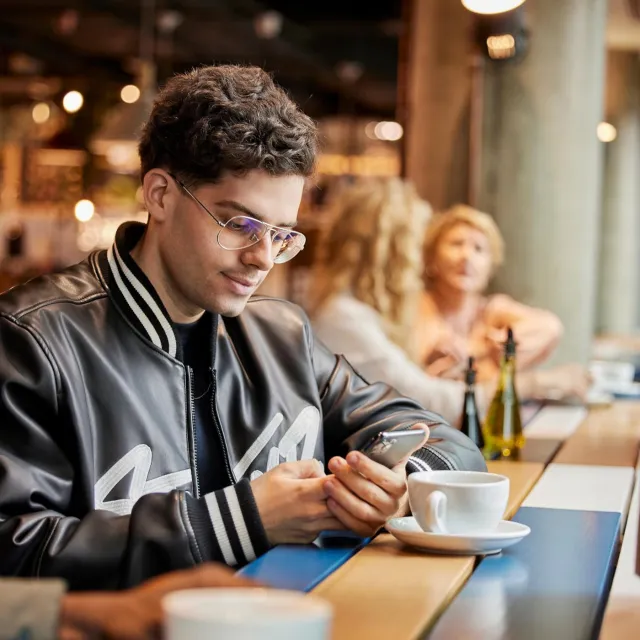 Image of man looking at phone in a coffee shop