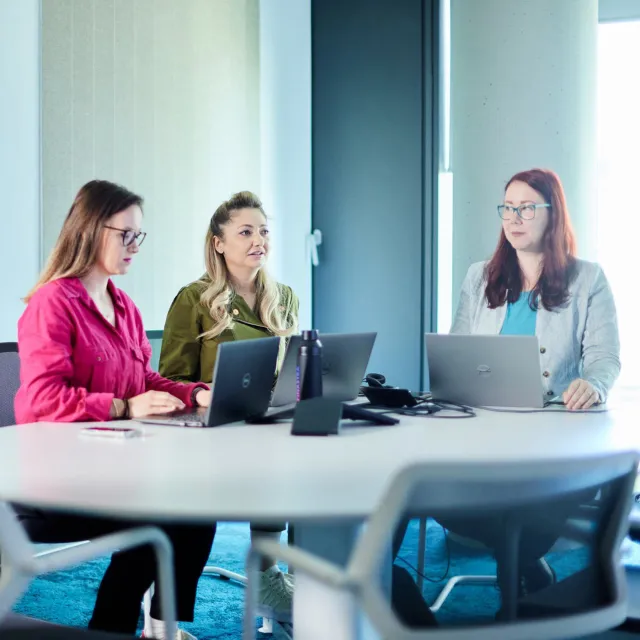 Image of three women discussing in a meeting room