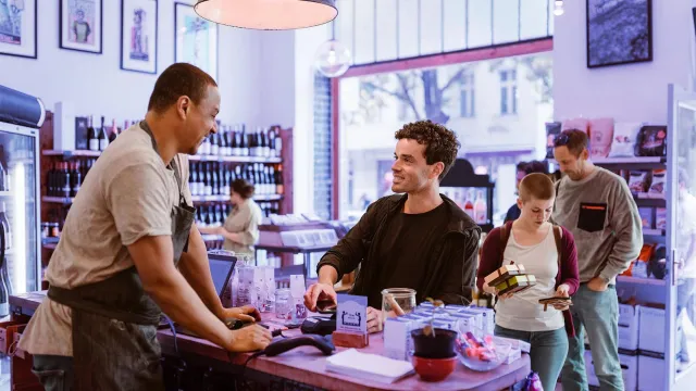 Customers making purchases at a local store counter in a modern retail environment.
