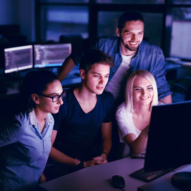 Software development team collaborating on code in a modern office environment.