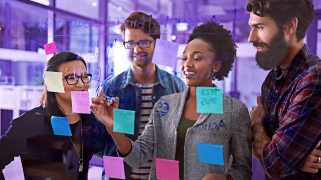 Image of team discussing post-its on a clear board