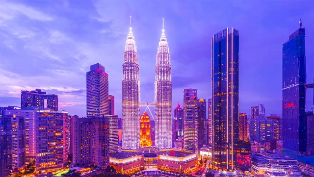 Kuala Lumpur skyline at dusk featuring the illuminated Petronas Twin Towers and modern skyscrapers.