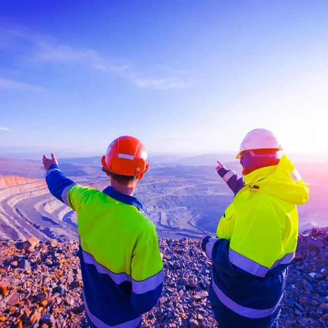 Mining Engineers worker on Open Pit Quarry overlooking ore mine, back view.