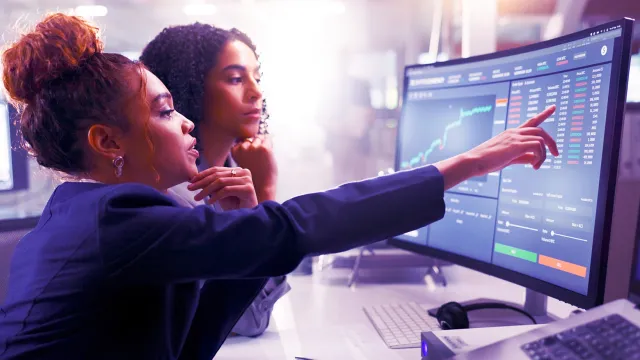 Analyzing financial data and stock performance on large trading monitor.