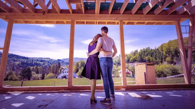 Image of couple inside a house under construction, looking outside the landscape
