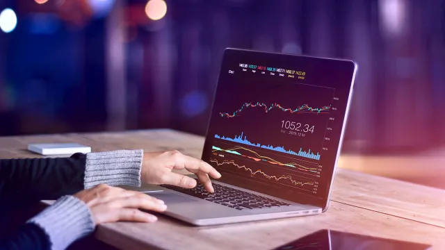 Analyzing stock market trends on a laptop with real-time financial charts.