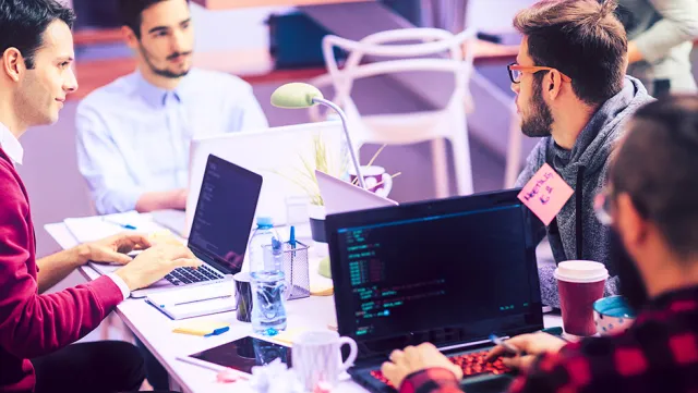 Developers collaborating on coding projects in a modern tech workspace.