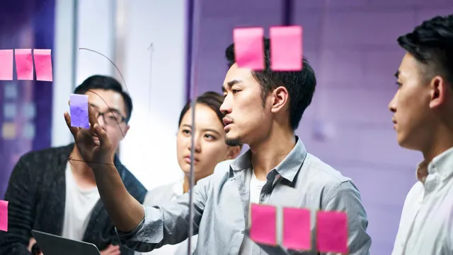 Creative team brainstorming with sticky notes in a collaborative office setting.