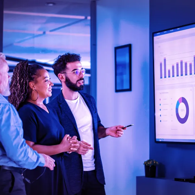 Company Operations Manager Holds Meeting Presentation. Diverse Team Uses TV Screen with Growth Analysis, Charts, Statistics and Data. People Work in Business Office.
