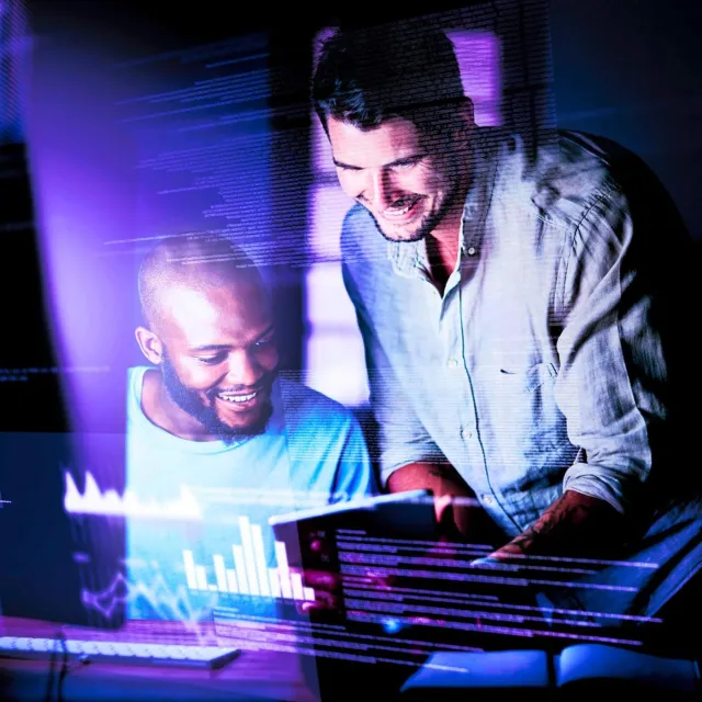 Team collaborating at a workstation, analyzing code and performance charts displayed on digital screens.