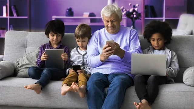 Family using digital devices together on a cozy living‑room sofa.