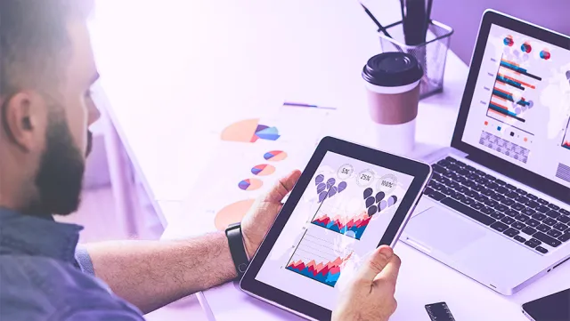 Reviewing digital analytics charts on a tablet at a modern workspace.