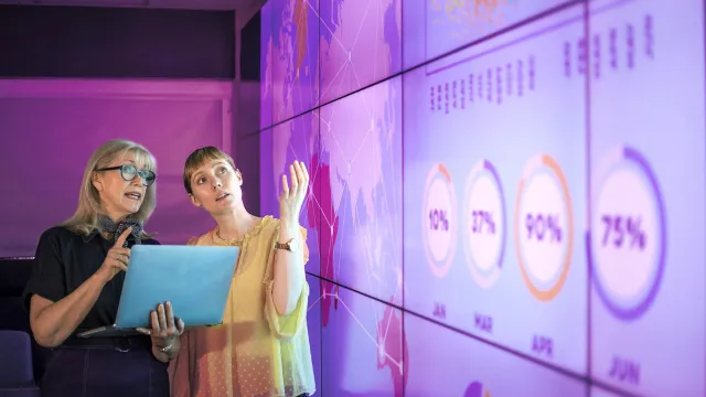 Image of two women looking at graphs on screen
