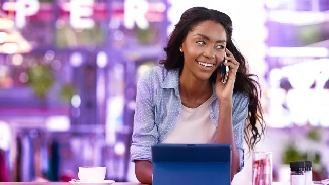 Image of woman on a mobile phone call, with tablet in front of her 