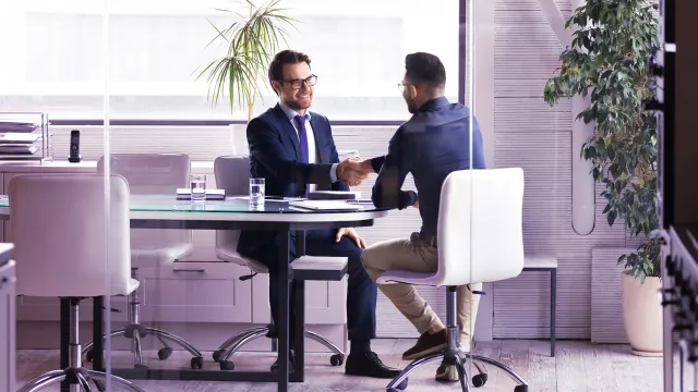 Image of two men shaking hands inside an office room