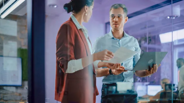 Image of two officemates discussing while standing