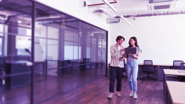 Image of officemates discussing while holding a laptop