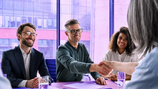Image of man shaking woman's hand in a team meeting